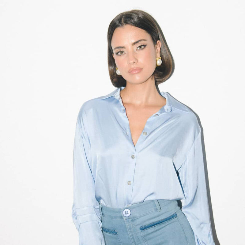 Woman wearing light blue satin shirt and high-waisted trousers from Cache Cache Clothing Lumiere collection